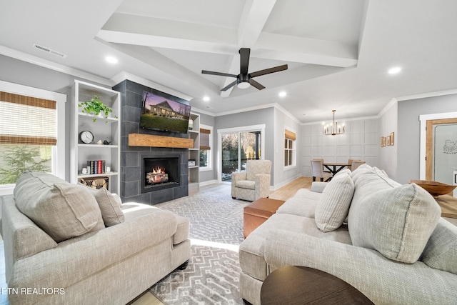 living room with ornamental molding, ceiling fan with notable chandelier, light hardwood / wood-style flooring, a tile fireplace, and beamed ceiling