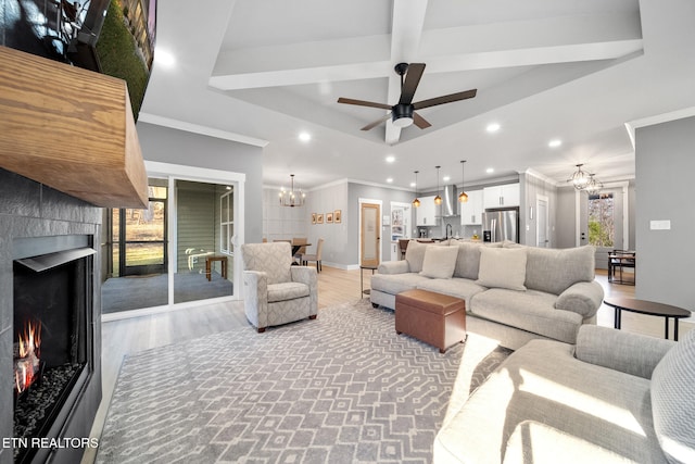 living room featuring ceiling fan with notable chandelier, light hardwood / wood-style floors, and crown molding