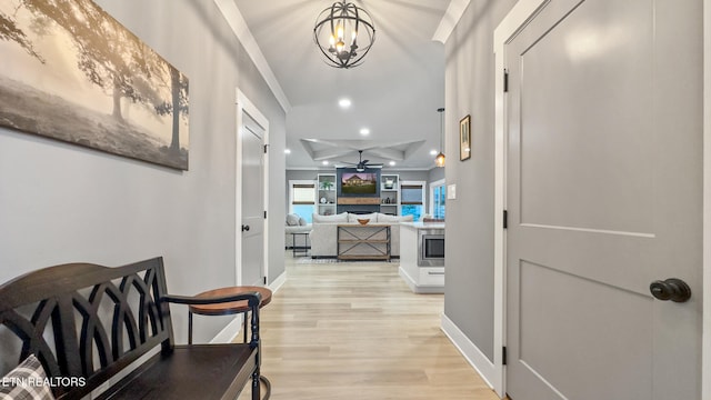 hall with crown molding, light hardwood / wood-style flooring, and a notable chandelier