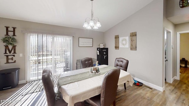 dining space with an inviting chandelier, hardwood / wood-style flooring, and lofted ceiling