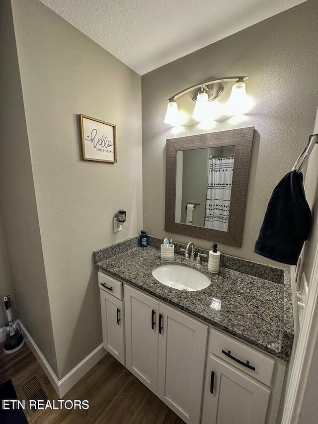 bathroom with vanity, wood-type flooring, and a textured ceiling