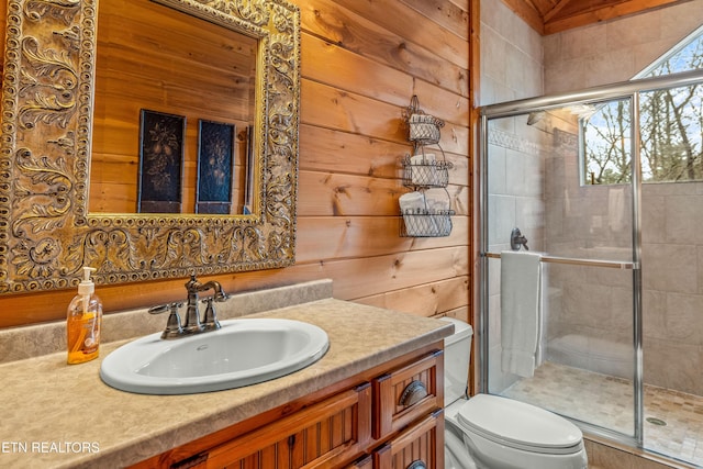 bathroom with an enclosed shower, vanity, toilet, and wood walls