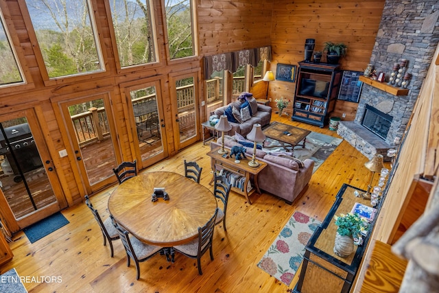 interior space with a towering ceiling, hardwood / wood-style floors, a fireplace, and wood walls