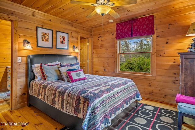 bedroom featuring wood ceiling, wooden walls, and light wood-type flooring