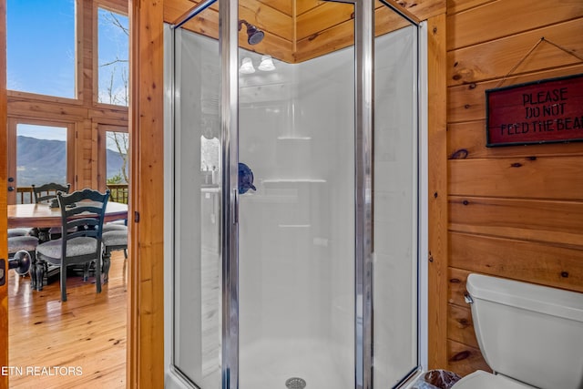 bathroom featuring walk in shower, wooden walls, hardwood / wood-style floors, and toilet