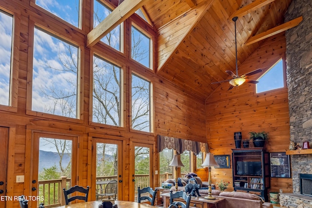 living room featuring a fireplace, plenty of natural light, ceiling fan, and wood walls