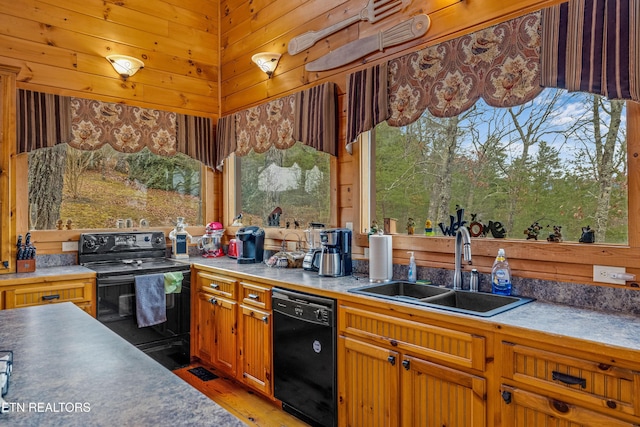 kitchen featuring sink, dark wood-type flooring, wood walls, and black appliances