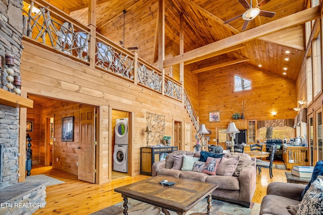 living room featuring stacked washer and dryer, wood ceiling, wooden walls, and light wood-type flooring