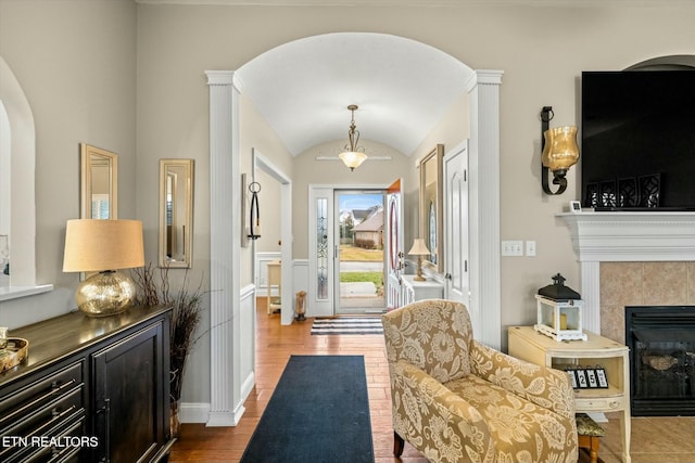 interior space featuring vaulted ceiling, hardwood / wood-style flooring, and a tile fireplace