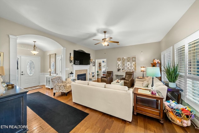 living room featuring light wood-type flooring, ceiling fan, and a tile fireplace