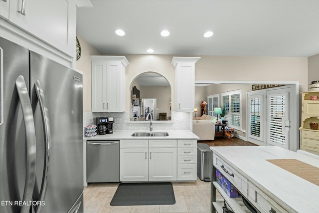 kitchen featuring white cabinets, stainless steel appliances, decorative backsplash, sink, and light tile patterned floors