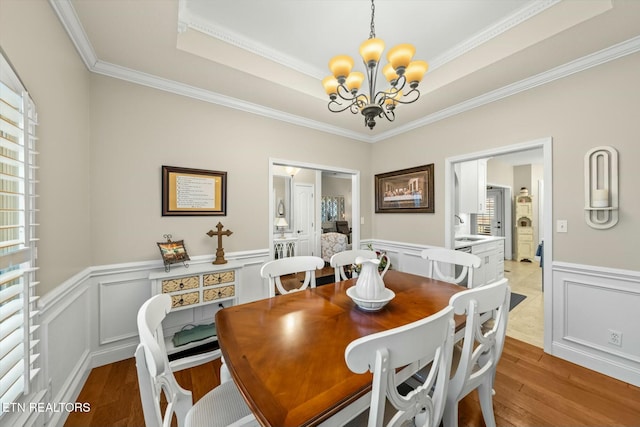 dining space with sink, ornamental molding, a chandelier, and light hardwood / wood-style flooring