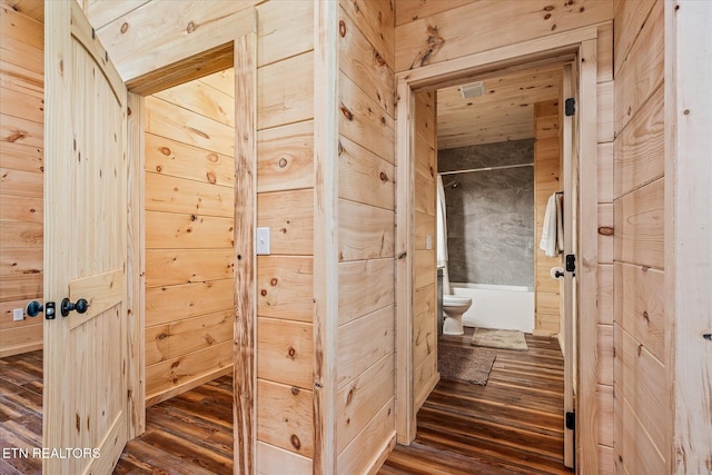 hall with dark wood-type flooring and wooden walls