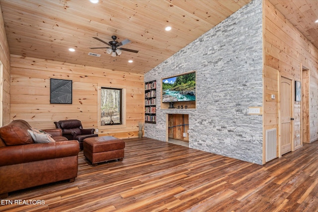 living room featuring high vaulted ceiling, hardwood / wood-style flooring, ceiling fan, and wooden walls