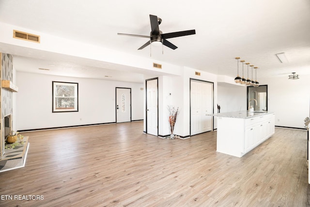 unfurnished living room with sink, light hardwood / wood-style flooring, and ceiling fan