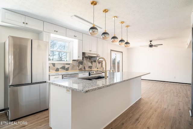 kitchen with white cabinetry, light stone countertops, an island with sink, and appliances with stainless steel finishes