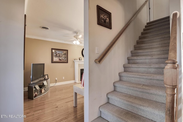 stairway with hardwood / wood-style floors, ornamental molding, and ceiling fan