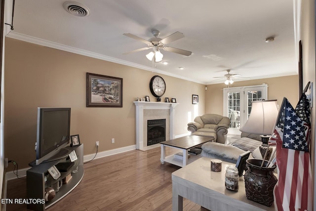 living room featuring wood-type flooring, ornamental molding, french doors, and ceiling fan