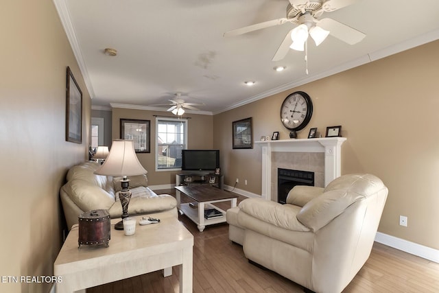 living room with ornamental molding, ceiling fan, a fireplace, and light hardwood / wood-style flooring