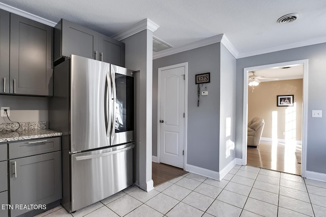 kitchen featuring crown molding, light tile patterned floors, stainless steel fridge, ceiling fan, and light stone countertops