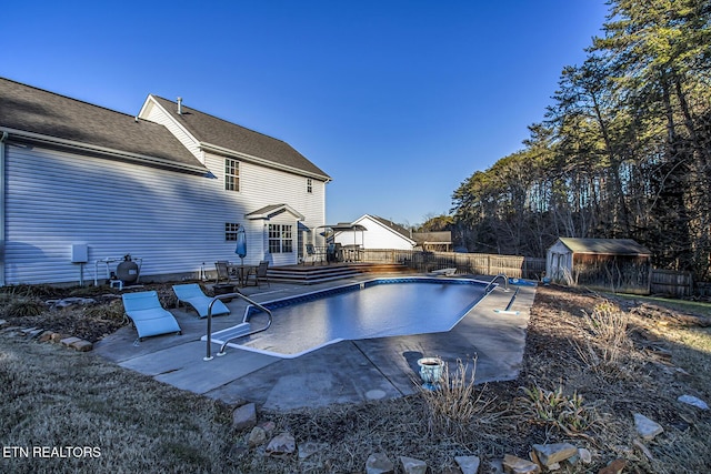 view of pool featuring a storage shed, a deck, and a patio