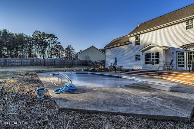 view of swimming pool featuring a diving board and a patio area