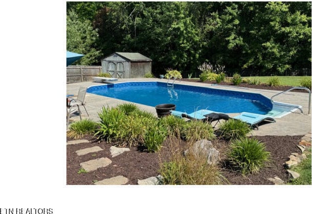 view of swimming pool with a diving board and a storage unit