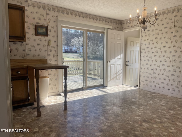 unfurnished dining area with a notable chandelier and a textured ceiling