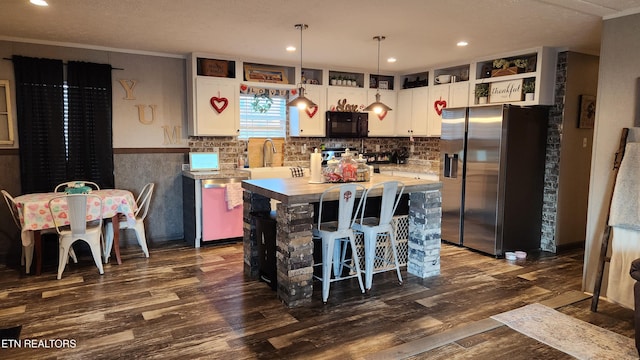 kitchen with dark hardwood / wood-style floors, a kitchen island, pendant lighting, white cabinetry, and appliances with stainless steel finishes