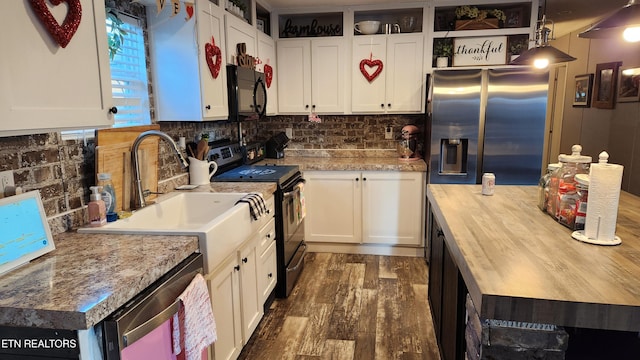 kitchen featuring dark wood-type flooring, appliances with stainless steel finishes, white cabinets, and decorative light fixtures