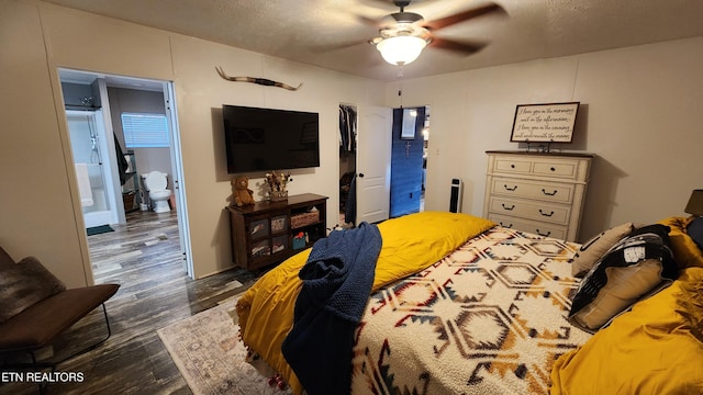 bedroom with ensuite bath, ceiling fan, dark wood-type flooring, and a textured ceiling