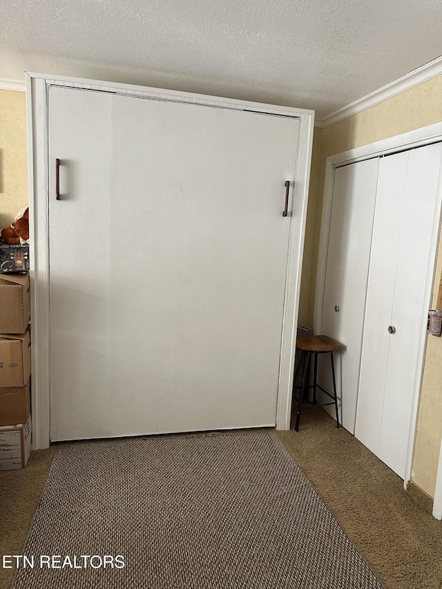 unfurnished bedroom featuring a textured ceiling, carpet flooring, and ornamental molding