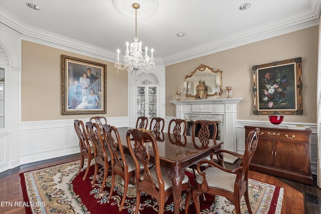 dining area with dark wood-type flooring, ornamental molding, and a chandelier