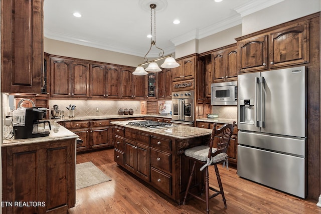 kitchen featuring dark brown cabinetry, stainless steel appliances, a center island, and ornamental molding