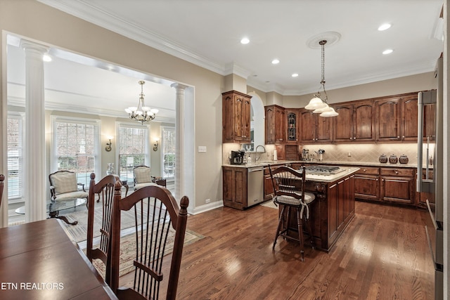 kitchen featuring hanging light fixtures, stainless steel appliances, a center island, and decorative columns