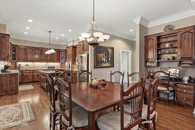 dining space featuring hardwood / wood-style flooring, ornamental molding, built in desk, and a notable chandelier