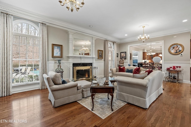 living room featuring wood-type flooring, a healthy amount of sunlight, a high end fireplace, and an inviting chandelier