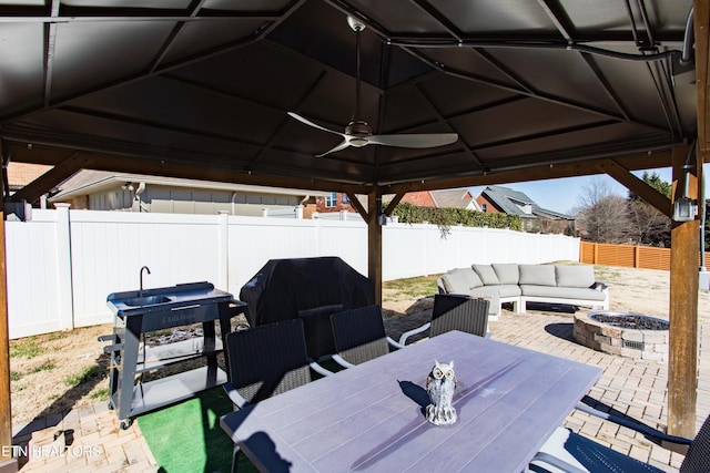 view of patio with ceiling fan, an outdoor living space with a fire pit, and a grill