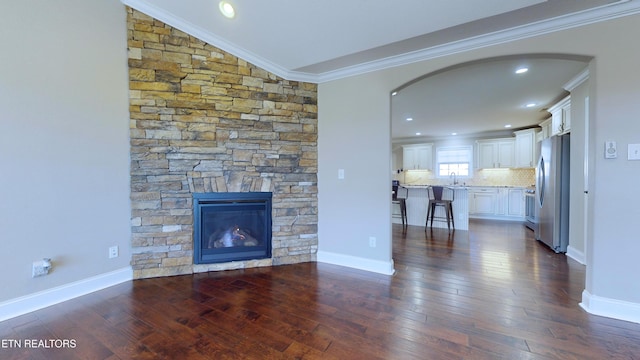 unfurnished living room with vaulted ceiling, dark hardwood / wood-style flooring, ornamental molding, and a fireplace