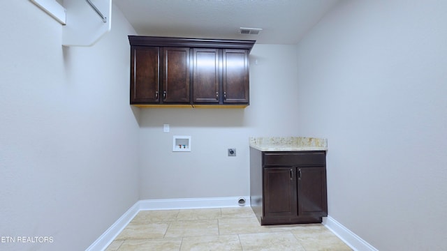 washroom with hookup for an electric dryer, light tile patterned flooring, hookup for a washing machine, a textured ceiling, and cabinets