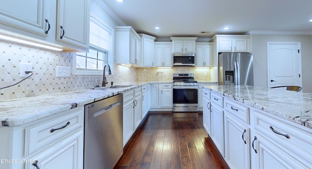 kitchen with appliances with stainless steel finishes, decorative backsplash, light stone countertops, white cabinets, and sink