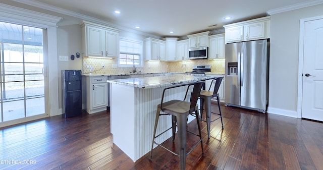 kitchen featuring dark wood-type flooring, white cabinets, stainless steel appliances, and a kitchen island