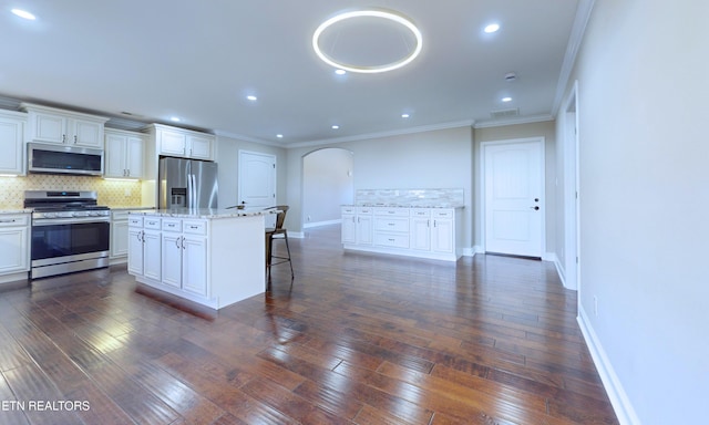 kitchen with white cabinets, a kitchen island, a kitchen bar, stainless steel appliances, and decorative backsplash