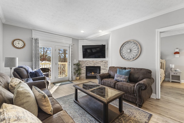 living room with a fireplace, a textured ceiling, light hardwood / wood-style flooring, and crown molding