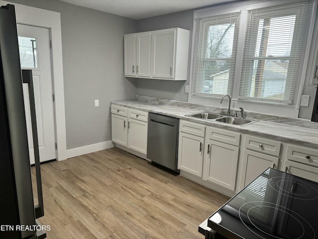 kitchen with sink, white cabinets, stainless steel dishwasher, and light hardwood / wood-style flooring