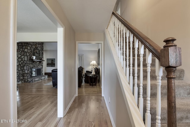 stairway with hardwood / wood-style flooring, a textured ceiling, and a fireplace