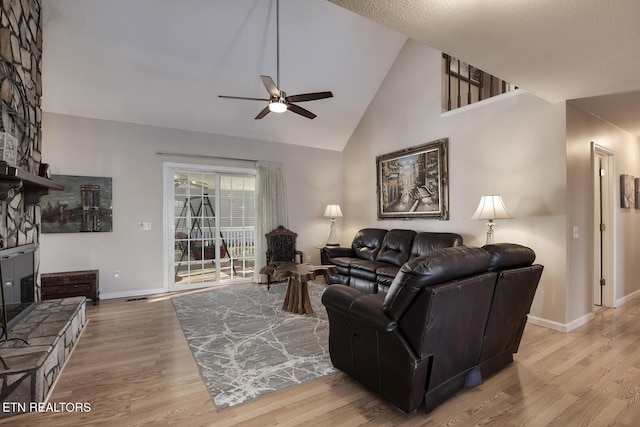 living room featuring a fireplace, high vaulted ceiling, ceiling fan, and light wood-type flooring