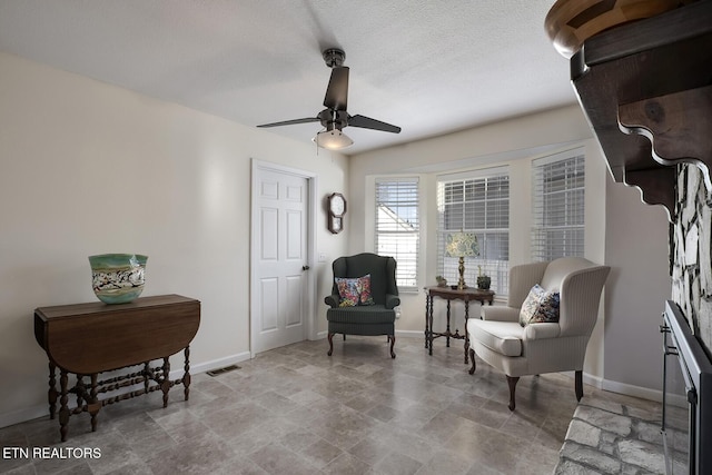 living area with ceiling fan and a textured ceiling