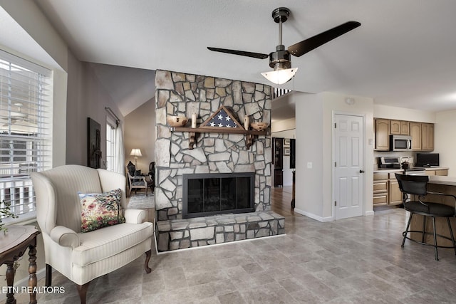 living room featuring a fireplace, vaulted ceiling, and ceiling fan