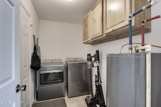 clothes washing area with washer and dryer, cabinets, and water heater